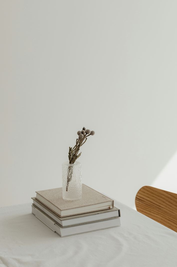 Photo of books on a table, with a vase and twigs.